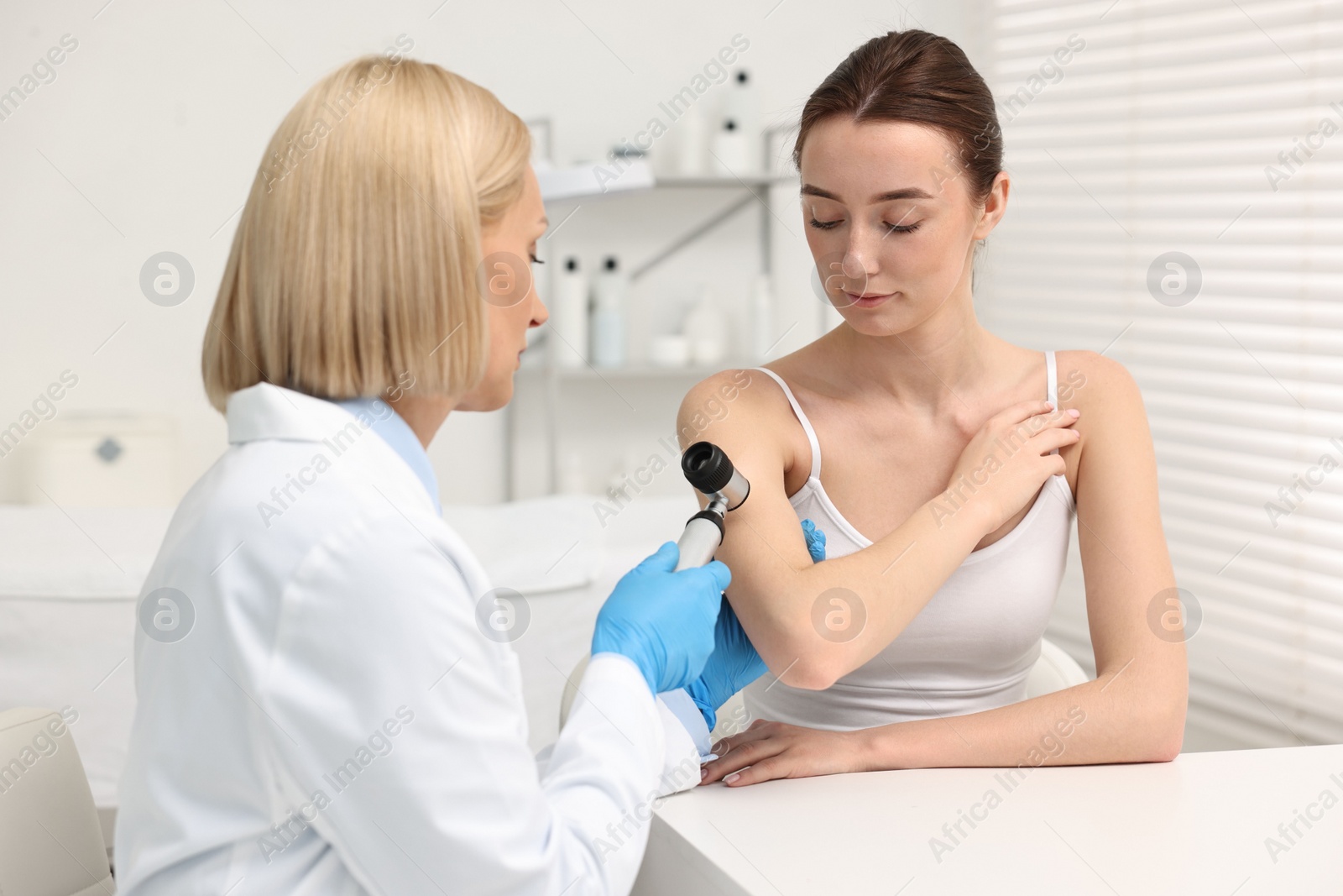 Photo of Dermatologist with dermatoscope examining patient in clinic