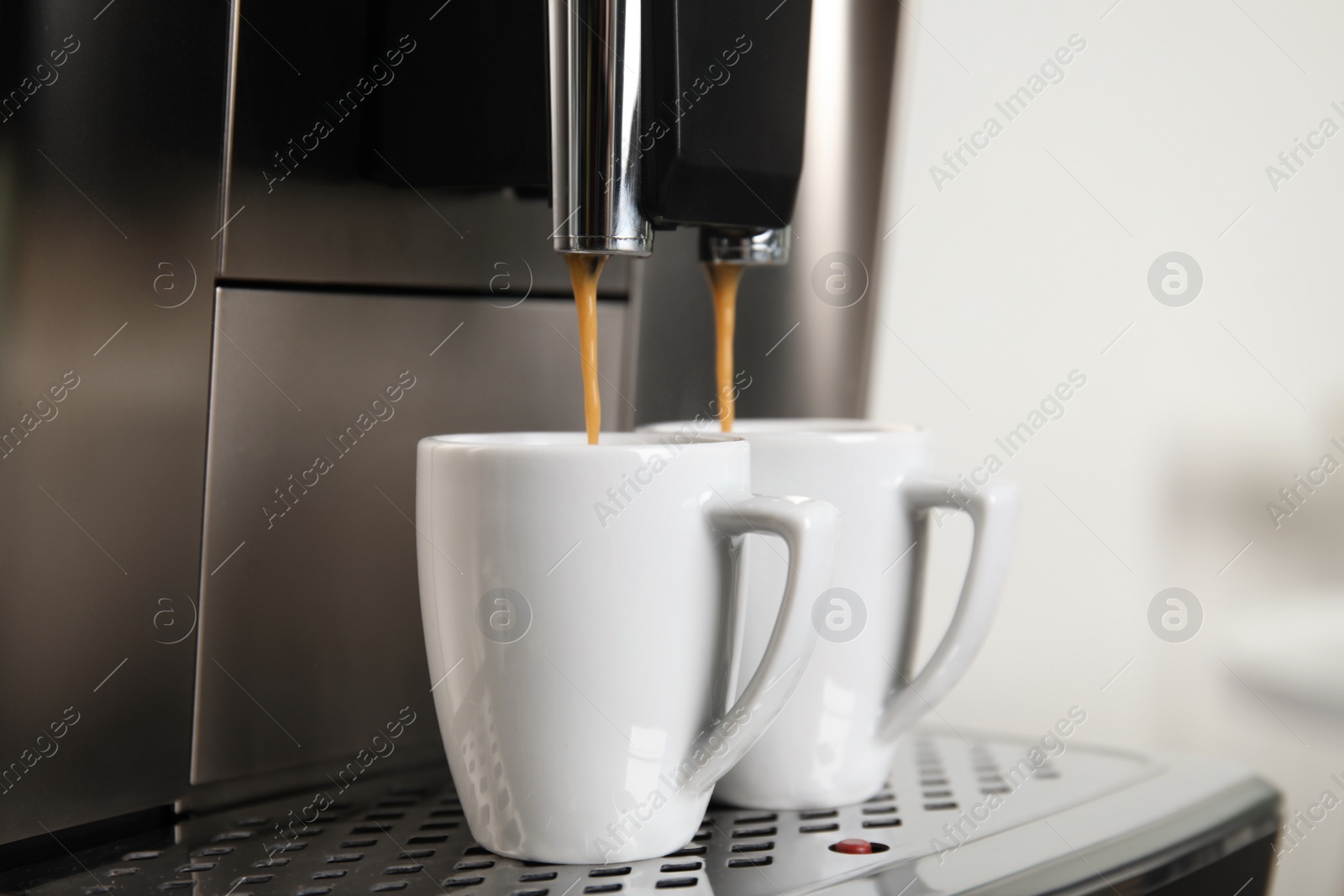 Photo of Espresso machine pouring coffee into cups against blurred background, closeup