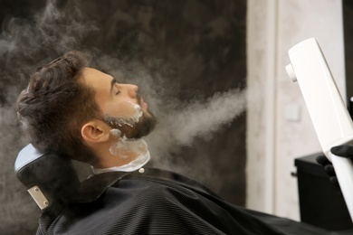 Hairdresser working with client at barbershop. Professional shaving service