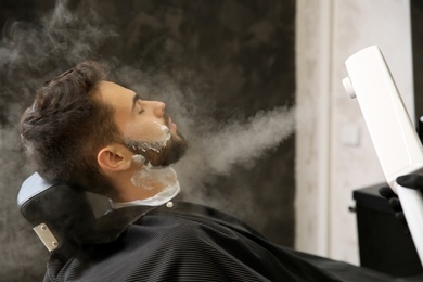 Photo of Hairdresser working with client at barbershop. Professional shaving service