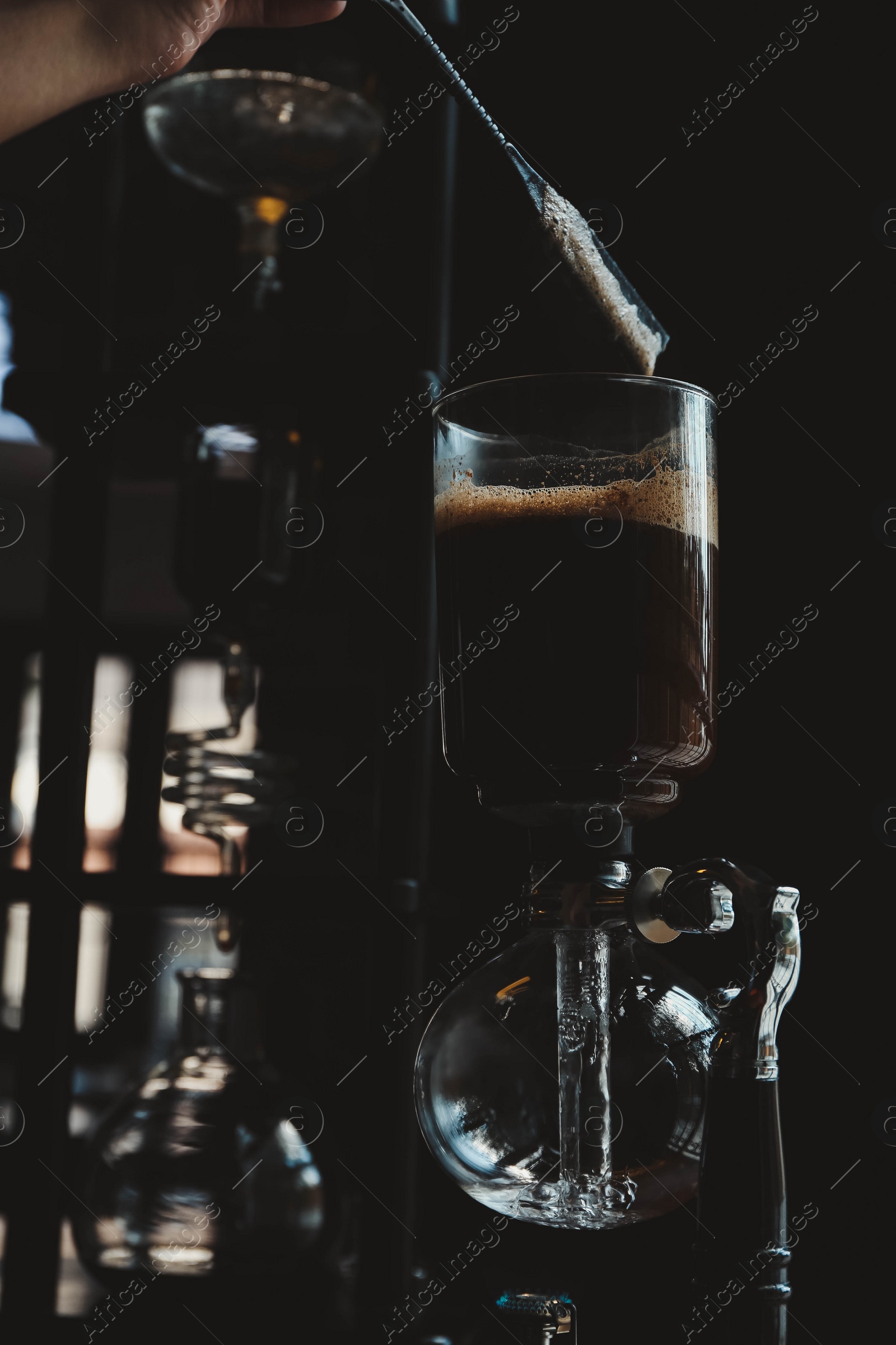 Photo of Barista making coffee with vacuum maker in cafe, closeup