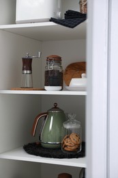 Manual coffee grinder and other appliances on shelving unit in kitchen