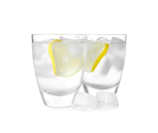Shot glasses of vodka with lemon slices and ice on white background