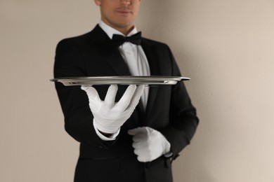 Photo of Butler with tray on beige background, closeup
