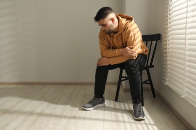 Photo of Sad man sitting on chair near window. Space for text