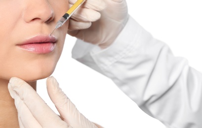 Young woman getting lips injection on white background, closeup. Cosmetic surgery