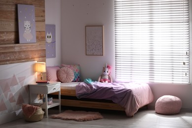 Photo of Bed with beautiful linens in children's room. Modern interior design