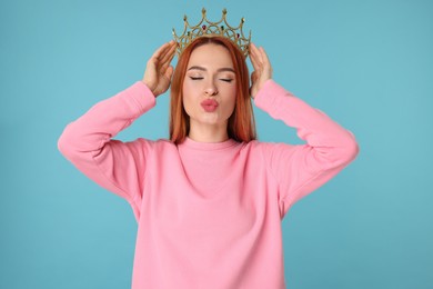 Photo of Beautiful young woman with golden crown on light blue background
