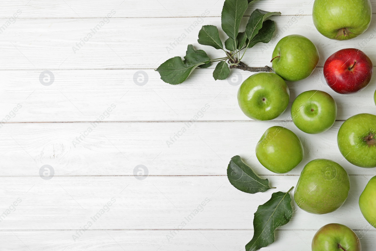 Photo of Red apple among green ones and space for text on wooden background, top view. Be different