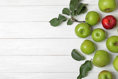 Red apple among green ones and space for text on wooden background, top view. Be different