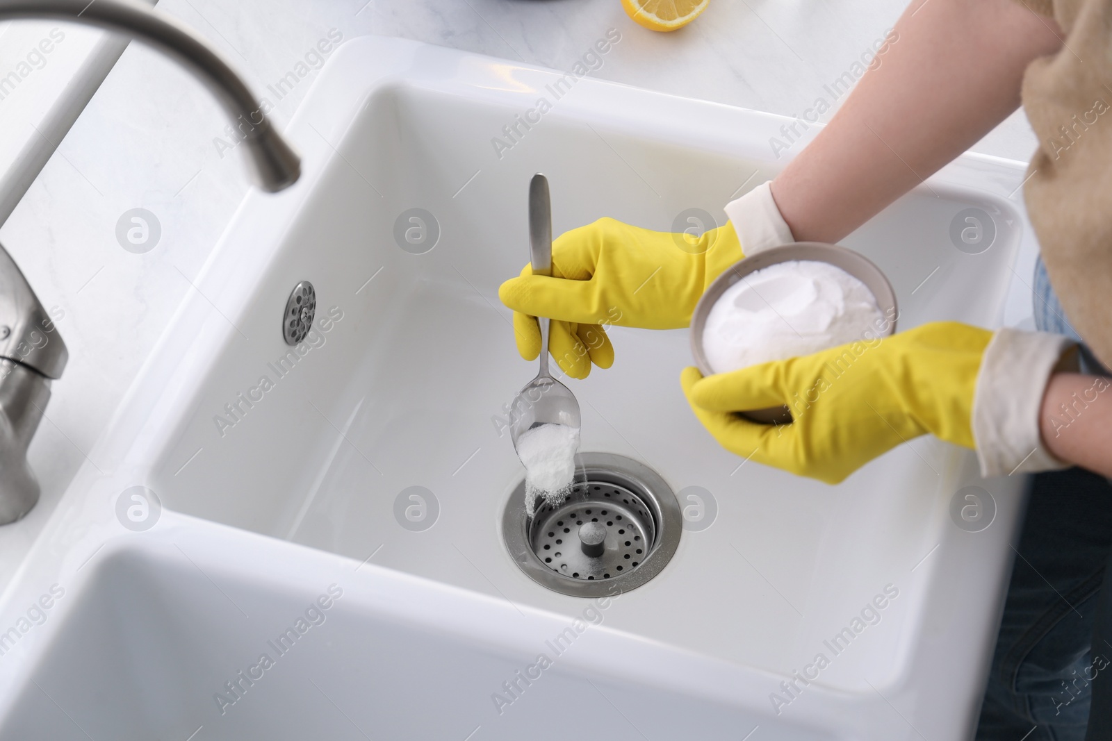 Photo of Woman using baking soda to unclog sink drain, closeup