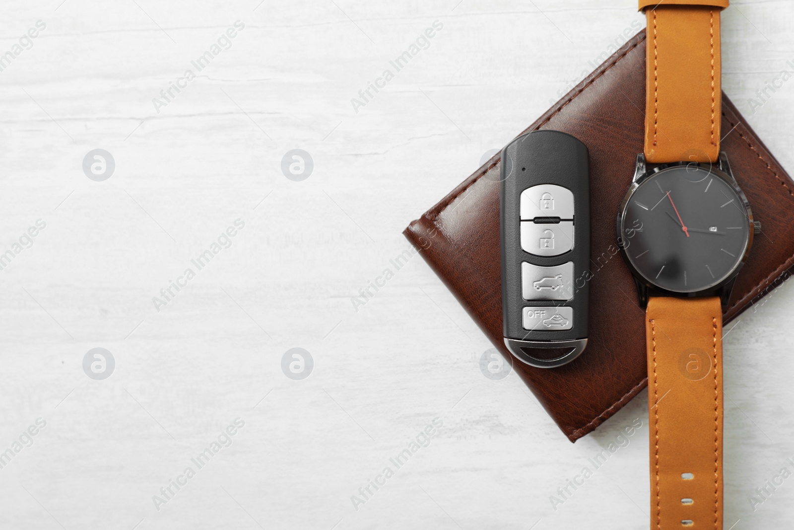 Photo of Wristwatch, remote car key and wallet on light background, top view. Space for text