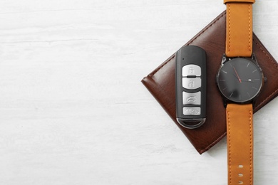 Photo of Wristwatch, remote car key and wallet on light background, top view. Space for text