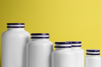 Photo of Many medicine bottles on yellow background, closeup. Space for text