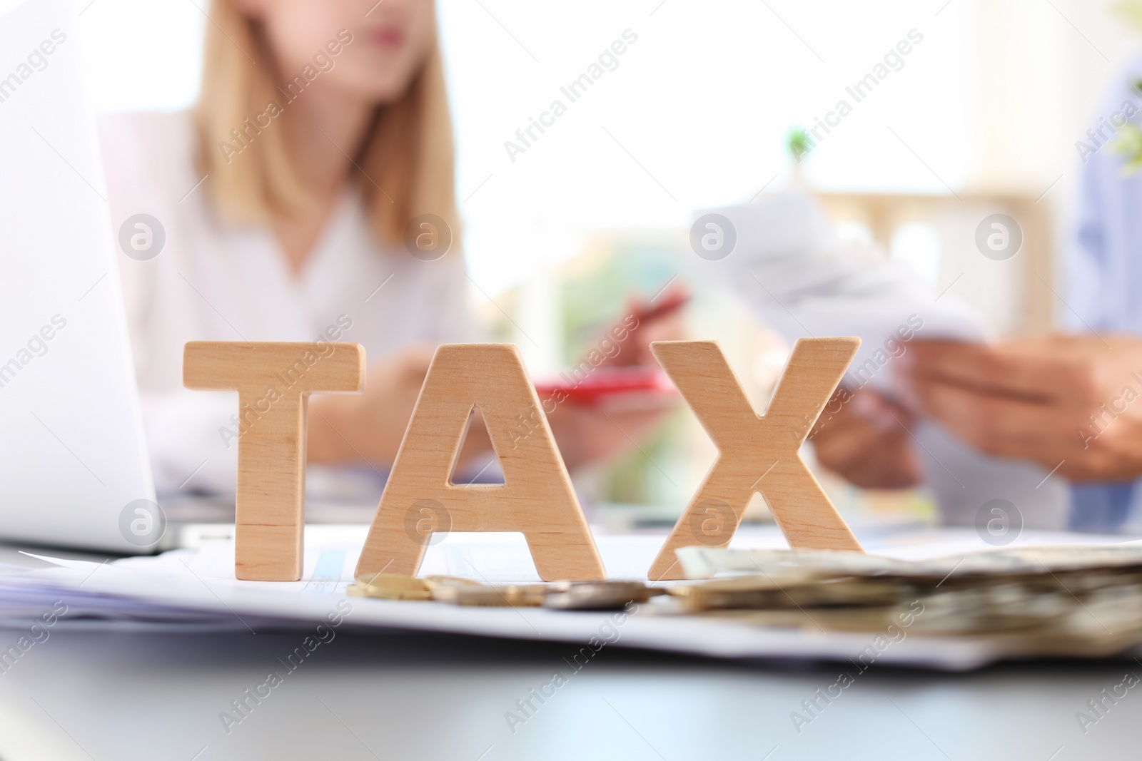 Photo of Word TAX and blurred accountants on background