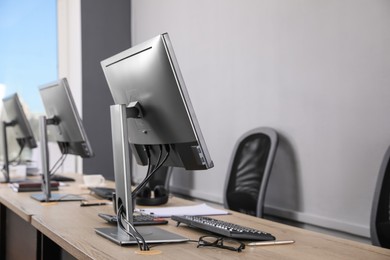 Photo of Open office interior. Modern workplaces with computers near light grey wall