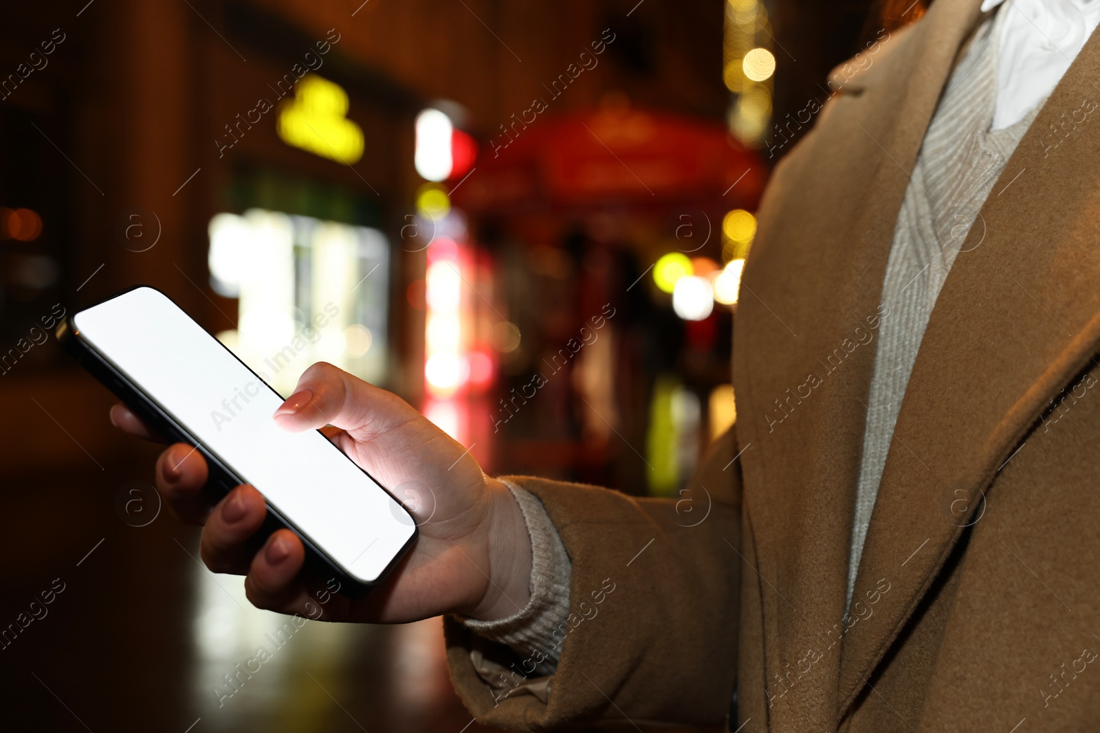 Photo of Woman with smartphone on night city street, closeup