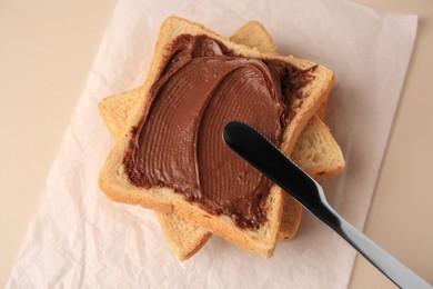 Tasty toast with chocolate paste and knife on light background, above view