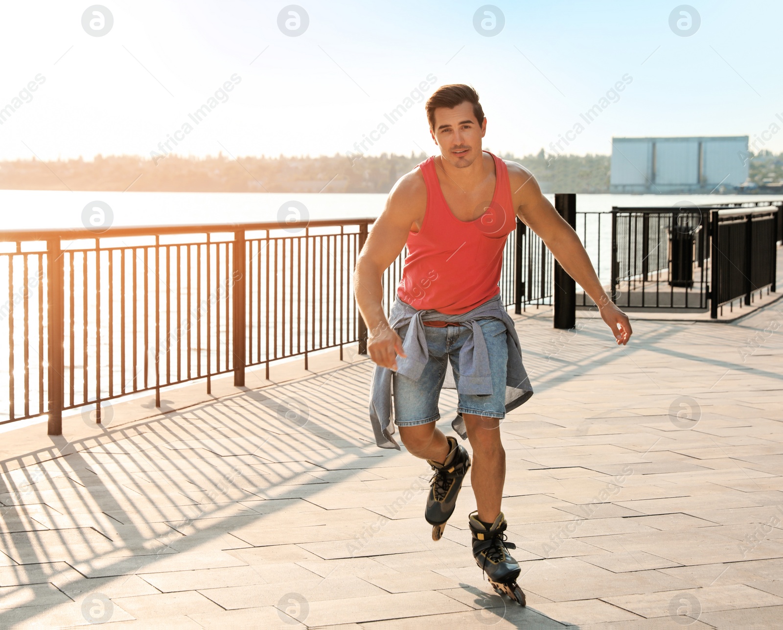 Photo of Handsome young man roller skating on pier near river, space for text