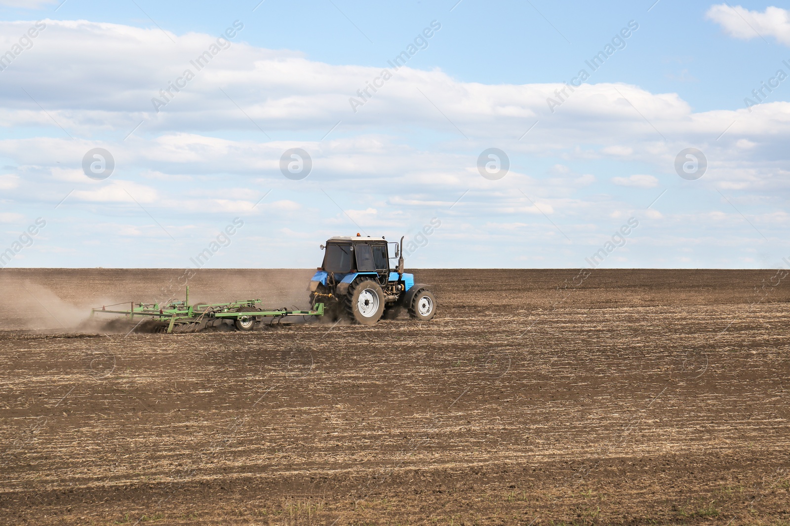 Photo of Tractor with planter cultivating field on sunny day. Agricultural industry