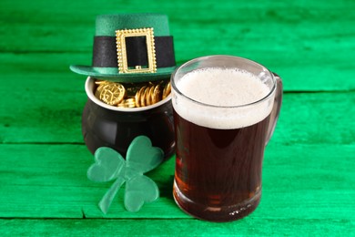 Image of St. Patrick's day. Beer, leprechaun hat, pot of gold and decorative clover leaf on green wooden table