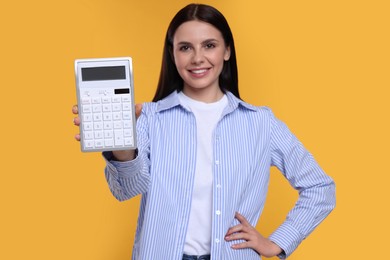 Photo of Smiling accountant against yellow background, focus on calculator