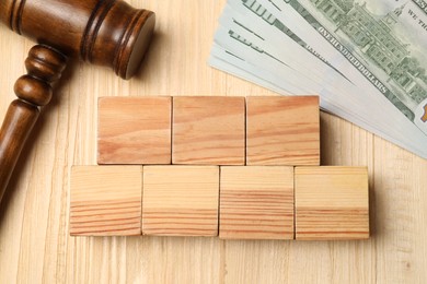 Tax law. Blank cubes, gavel and dollar banknotes on wooden table, flat lay