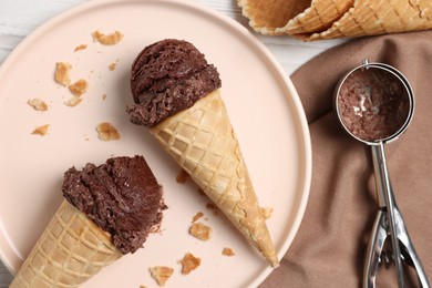 Chocolate ice cream scoops in wafer cones on table, flat lay