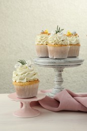 Photo of Tasty Easter cupcakes with vanilla cream on light wooden table