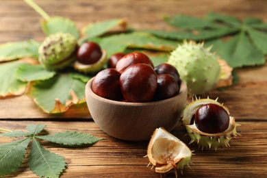 Horse chestnuts and leaves on wooden table