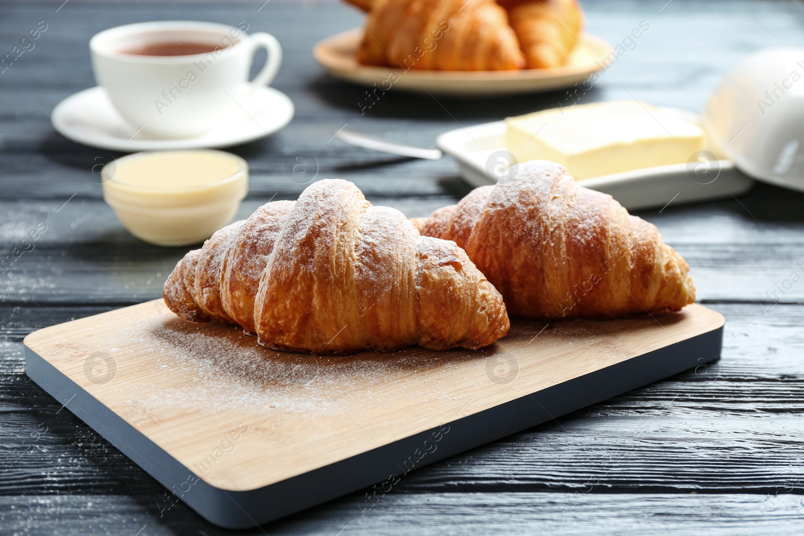 Photo of Board with tasty croissants on dark wooden table. French pastry