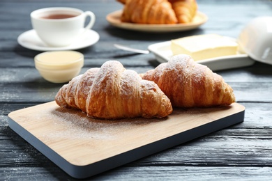 Photo of Board with tasty croissants on dark wooden table. French pastry