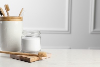 Photo of Bamboo toothbrushes and jar of baking soda on white table, space for text