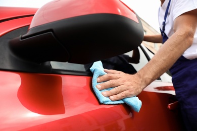 Photo of Man cleaning red auto with duster, closeup. Car wash service