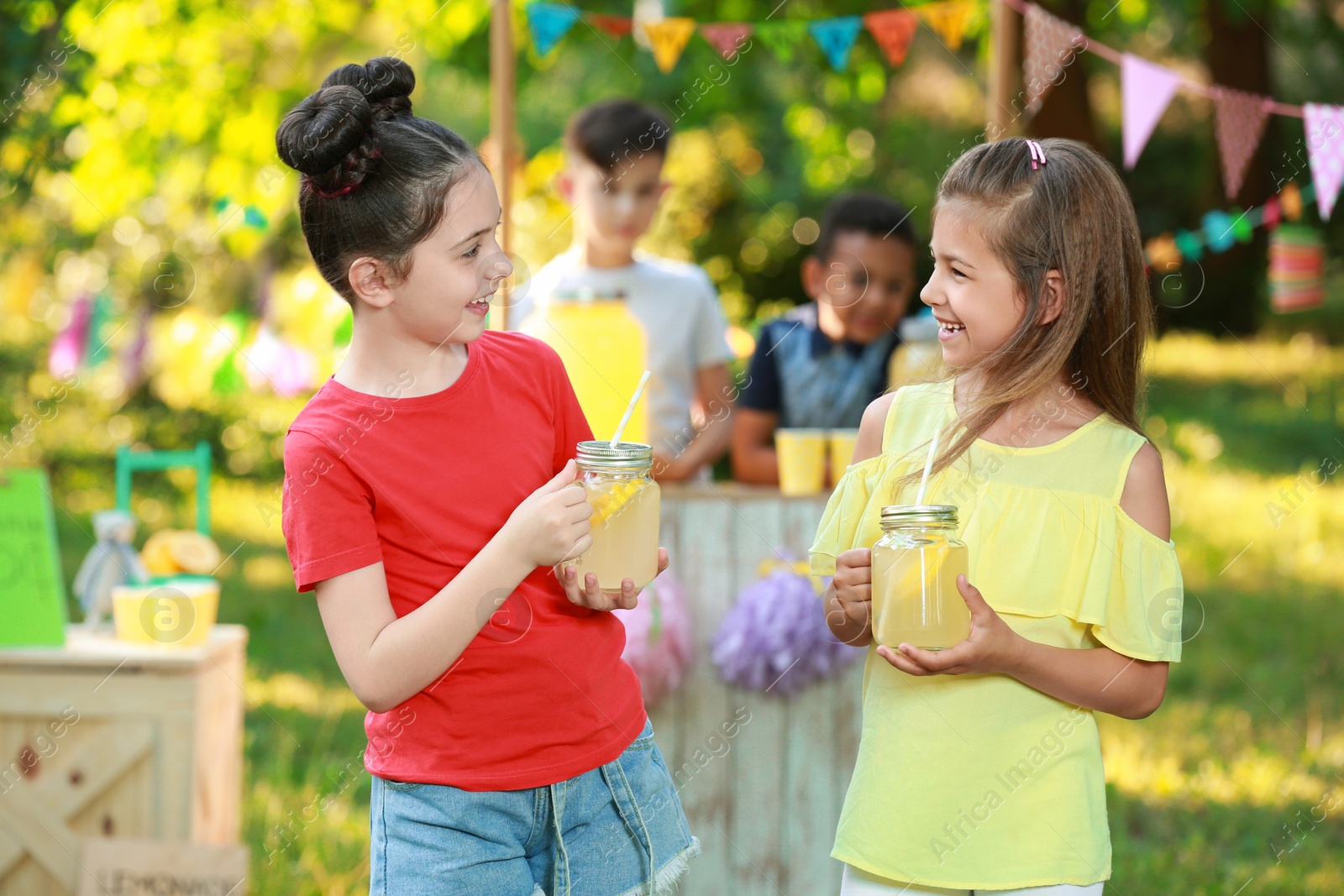 Photo of Cute little girls with natural lemonade in park. Summer refreshing drink