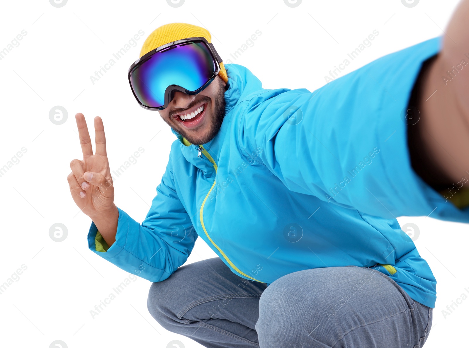 Photo of Smiling young man in ski goggles taking selfie and showing peace sign on white background