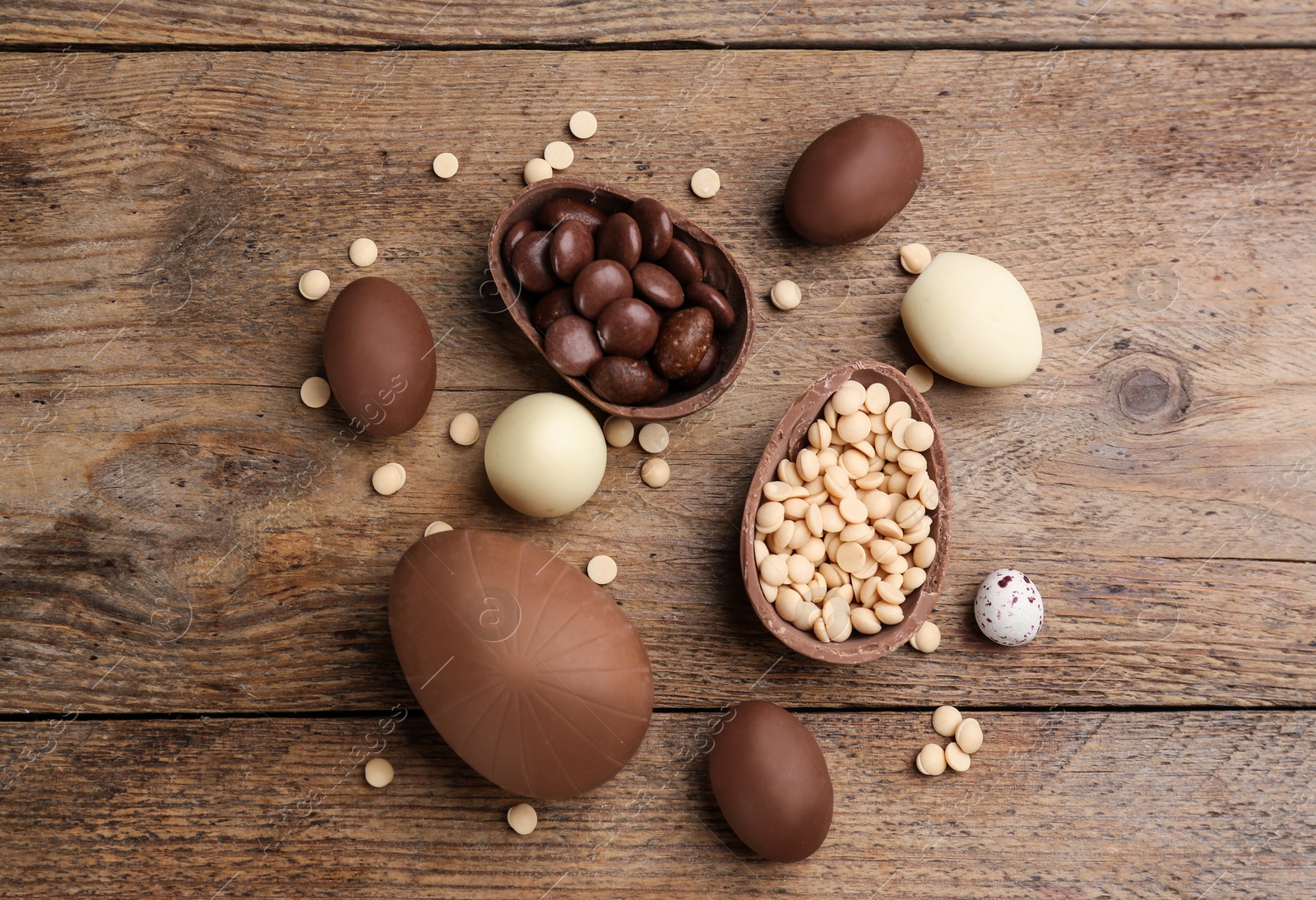 Photo of Sweet chocolate eggs and candies on wooden table, flat lay