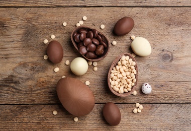 Photo of Sweet chocolate eggs and candies on wooden table, flat lay