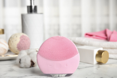 Photo of Modern face cleansing brush on marble table. Cosmetic accessory