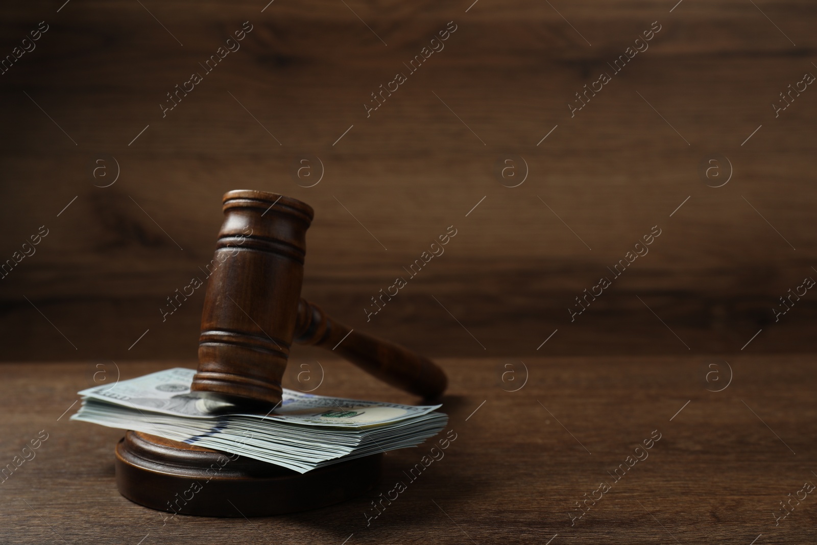 Photo of Law gavel with stack of dollars on wooden table, closeup. Space for text