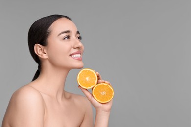 Photo of Beautiful young woman with pieces of orange on grey background. Space for text