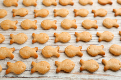 Delicious goldfish crackers on white wooden table, closeup