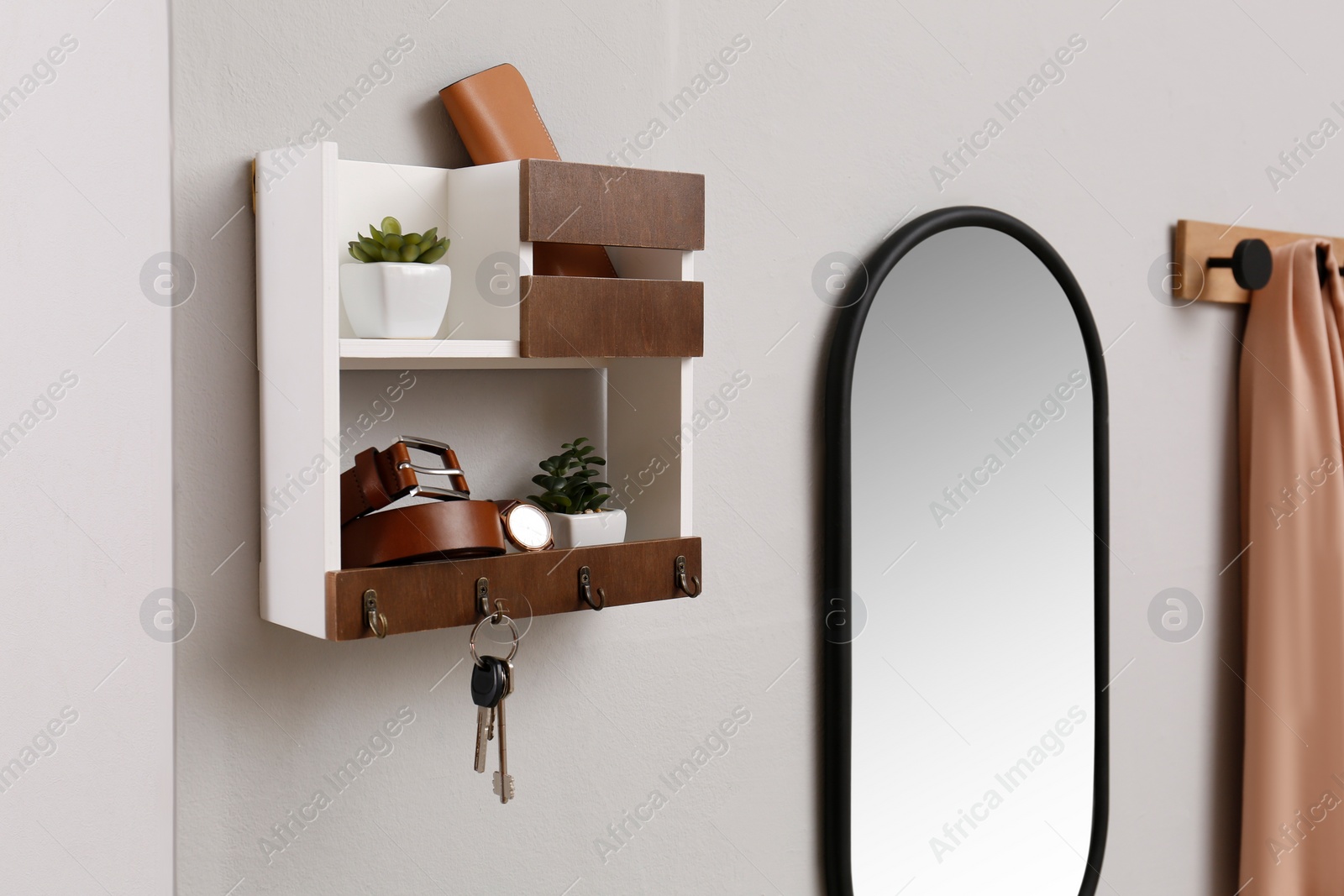 Photo of Hallway interior with stylish accessories and wooden hanger for keys on white wall
