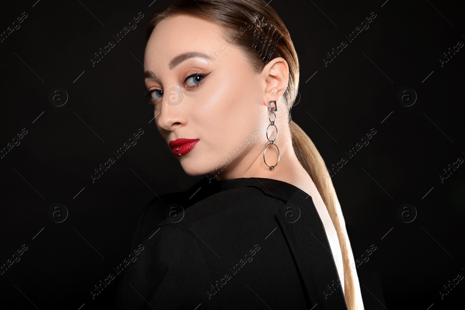 Photo of Young woman with lip piercing on black background