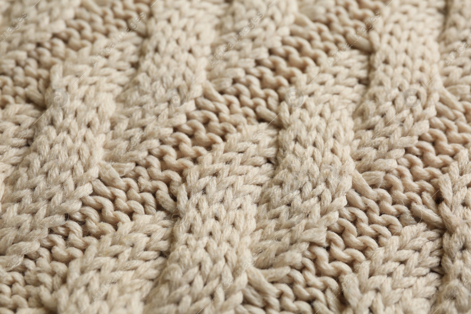 Photo of Beige knitted fabric with beautiful pattern as background, closeup
