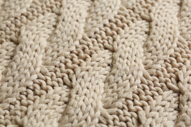 Beige knitted fabric with beautiful pattern as background, closeup