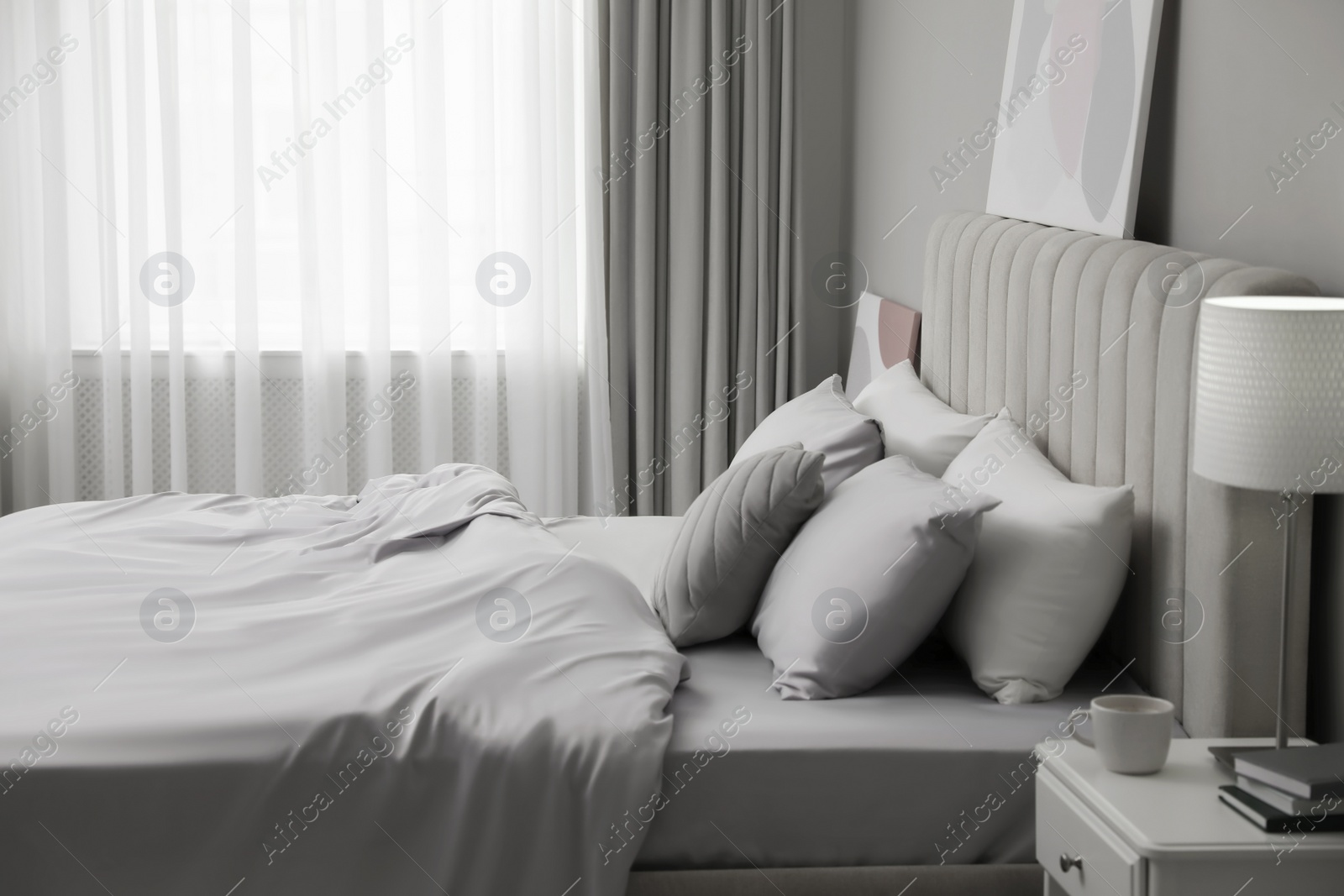 Photo of Cozy bed with soft silky bedclothes in light room