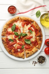 Delicious Margherita pizza and ingredients on white wooden table, top view