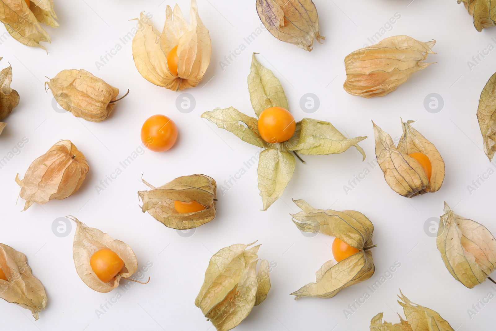 Photo of Ripe physalis fruits with calyxes on white background, flat lay