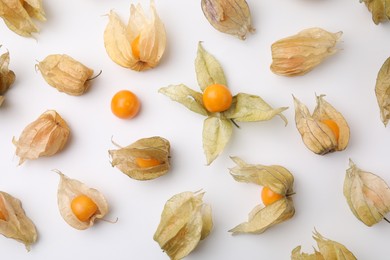 Ripe physalis fruits with calyxes on white background, flat lay